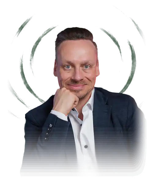 Fabian Henzler in a navy blazer, hand on his chin, smiling in front of forest green with drawn rings