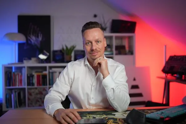 Fabian Henzler in a white shirt at a desk, hand at his chin