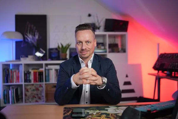 Fabian Henzler in a navy blazer at a desk, hands folded
