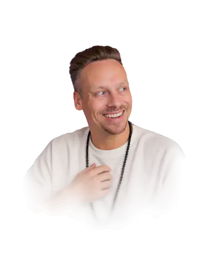 Fabian Henzler in a white shirt with mala beads, laughing, his hand on his heart, in front of forest green with drawn rings